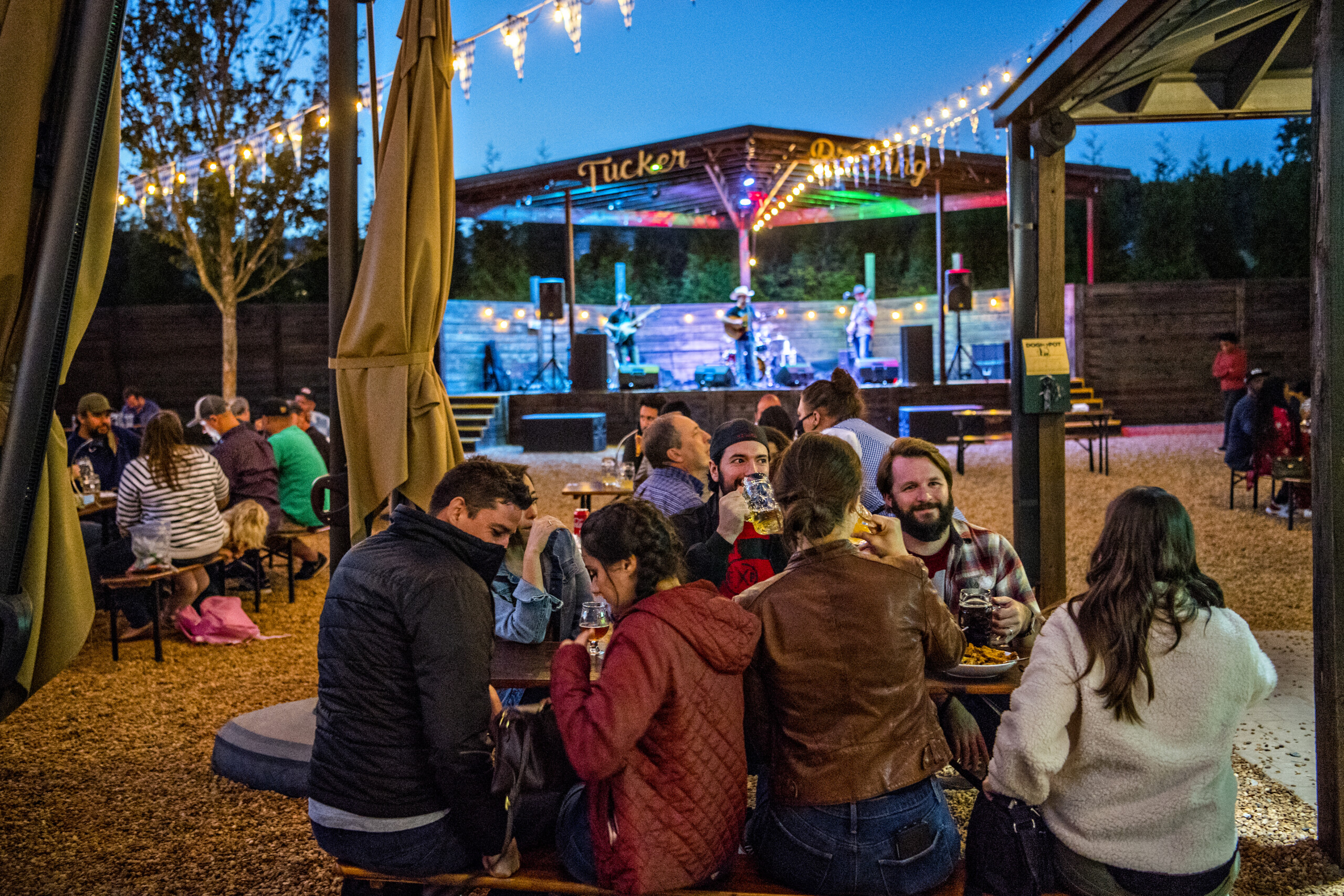 People enjoying drinks at outdoor brewery with live band