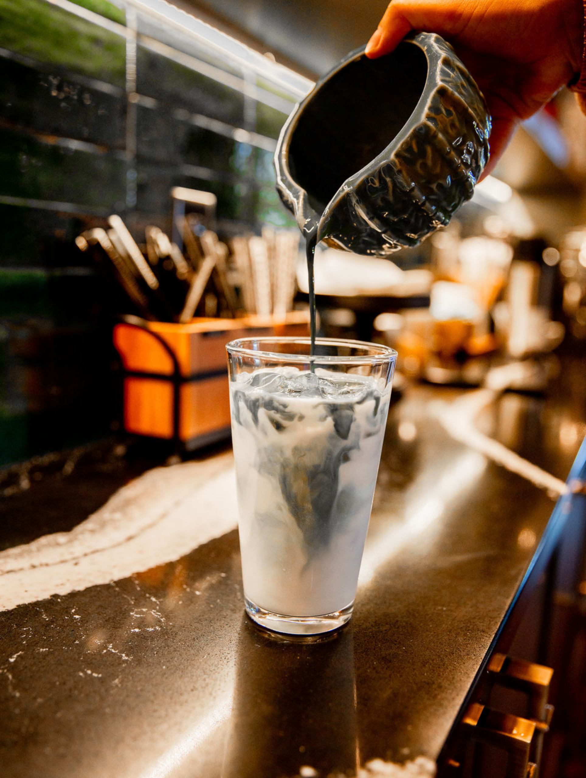 Coffee being poured into iced milk drink